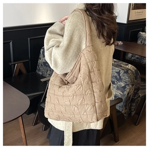 Détail d'un grand sac cabas matelassé beige dans un café aux tons chauds et cosy