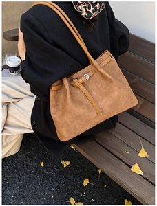 Vintage brown textured tote bag with buckle detail on a street bench with autumn leaves