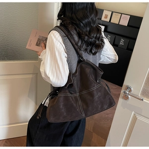 Detail of dark brown tote bag featuring white contrast stitching and drawstring closure