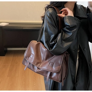 Detailed side view of vintage brown leather underarm bag with accordion fold and flap
