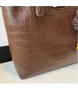 Detail of coffee brown tote bag featuring crocodile embossed texture and gold lettering