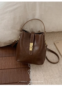 Detailed view of dark brown bucket bag with gold clasp and detachable shoulder strap