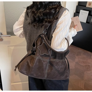 Detail of dark brown tote bag featuring white contrast stitching and a star charm