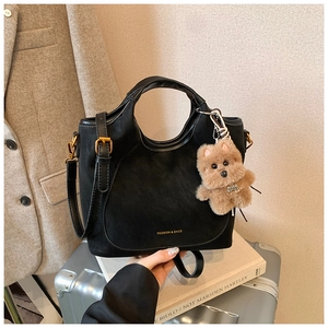 Detail of black suede tote bag with puppy charm and Fashion & Bags logo print