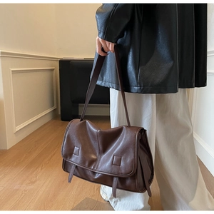 Detail of vintage dark brown leather messenger bag showing supple texture and stylish straps