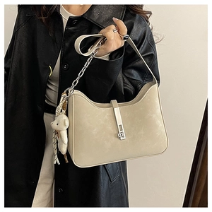 Detail of beige hobo bag with silver chain and cute plush bear charm on black coat