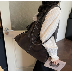 Detail of deep brown suede tote with white stitching and star pendant decoration