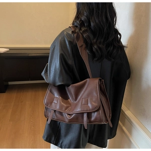 Close-up of vintage brown leather messenger bag featuring adjustable strap and flap detail