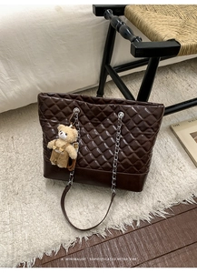 Close-up of dark brown quilted tote bag with silver chain strap and a cute bear charm