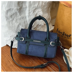 Détail du sac à bandoulière en daim bleu avec passepoil en cuir et boucle métallique