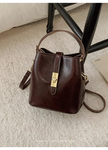Detail of vintage dark brown bucket bag with gold clasp on plush rug background