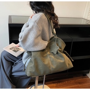 Olive green tote bag with white stitching detail worn by model in casual lifestyle setting