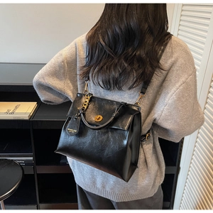 Close-up of black retro leather backpack with golden metal lock and stylish brand tag