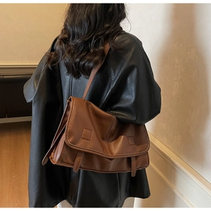 Brown vintage messenger bag shown in use, featuring matte leather and large flap closure
