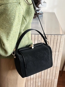 Elegant black doctor bag handbag with gold clasp and detachable strap shown on a model