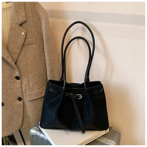 Detail of black woven leather tote bag with buckle strap on a silver suitcase