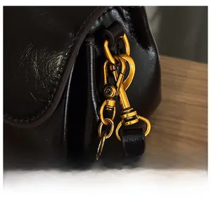 Close-up of bronze metal hook and oil wax leather texture on a vintage black handbag