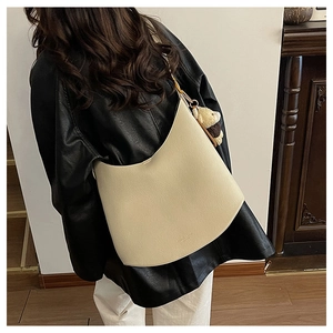 Vue portée d'un sac à bandoulière blanc crème avec un joli charme d'ours brun