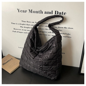 Détail du sac cabas matelassé noir avec texture bouffante sur une surface minimaliste