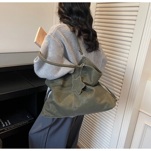 Detail of olive green leather tote bag featuring contrast stitching and star charm pendant