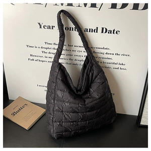 Détail de la texture d'un sac cabas noir matelassé avec décor minimaliste et livre