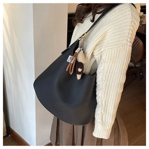 Vue détaillée du sac Hobo en cuir noir avec bandoulière réglable et breloque peluche