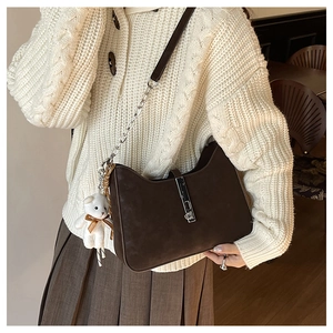 Detail of hobo bag with silver piston closure and chain strap on knit sweater