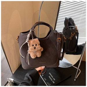Deep brown matte leather bucket bag detail with plush puppy charm and mirror reflection