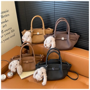 Detail of colorful leather bucket bags with plush rabbit charms on a leather sofa