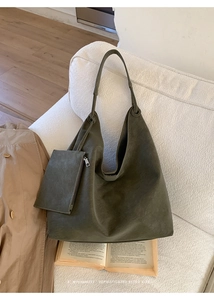 Detail view of large olive green tote bag with matching pouch on a white sofa