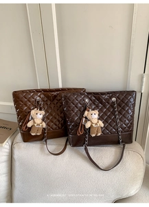 Detail of dark brown quilted tote bag with metal chain strap and cute bear charm