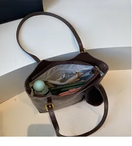 Macro view of brown crocodile pattern bucket bag showing spacious interior compartment
