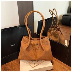 Detail of brown woven tote bag with adjustable side drawstring on a wooden table