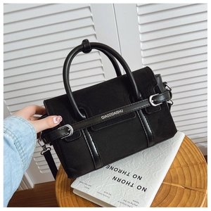 Gros plan d'un sac à bandoulière en toile noire avec poignées en cuir et détails argent