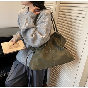 Detailed view of olive green tote bag featuring white cross-stitching and side drawstrings