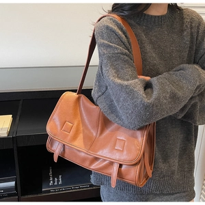 Detailed side view of caramel brown leather satchel bag with buckle straps and matte finish