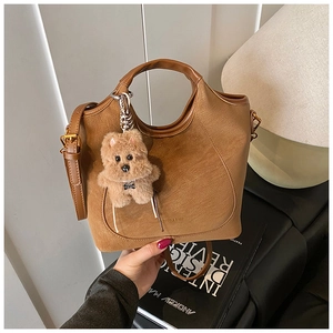 Close-up of brown lychee texture bucket bag featuring a cute plush bear charm detail