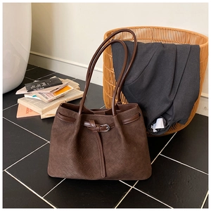 Detail of dark brown woven texture tote bag featuring leather buckle strap and retro style