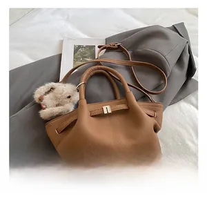 Detail of brown faux leather bucket bag with gold hardware and plush bear charm