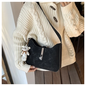 Close-up of black matte shoulder bag with silver buckle and cute white bear charm