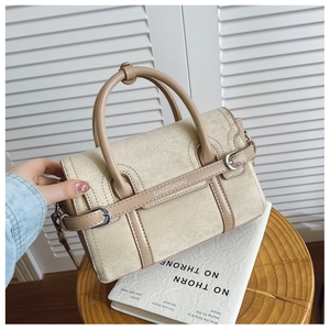 Détail du sac bandoulière beige avec coutures en daim et boucle métallique argentée
