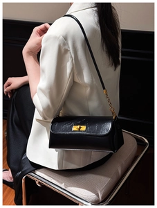 Detail of glossy wrinkled leather black shoulder bag with gold twist lock and chain strap