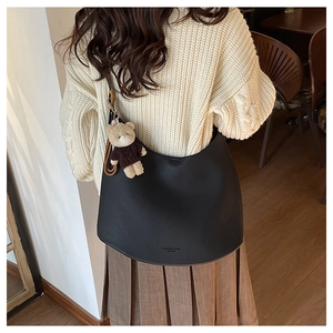Détail du sac demi-lune en cuir noir avec un porte-clé ours en peluche marron