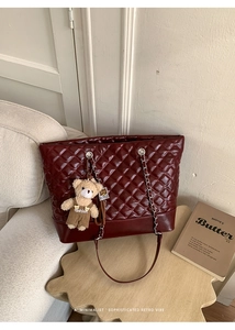 Detail of burgundy quilted tote bag with silver chain strap and cute bear charm