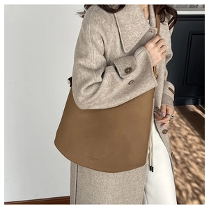 Sac à bandoulière en cuir marron avec texture litchi et détails gaufrés au bas