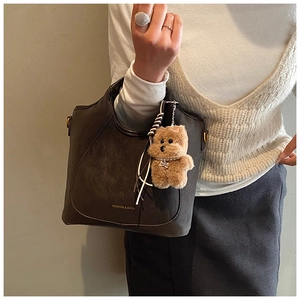 Detail of matte leather texture on large bucket bag with cute plush bear charm