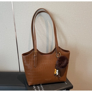 Detailed view of brown crocodile texture leather bucket bag with plush charm and logo