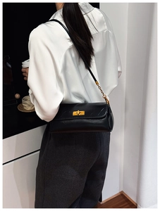 Close-up of black lychee grain leather shoulder bag with golden metallic twist lock