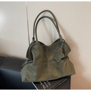 Close-up of olive green leather tote bag with contrast stitching and star pendant