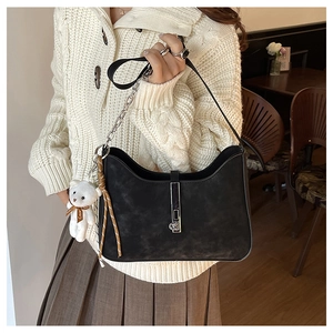Close-up of black suede hobo bag with silver buckle and cute white bear charm
